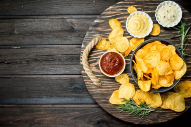 Farklı sos ve biberiye patates cipsi. Ahşap bir arka plan üzerinde.