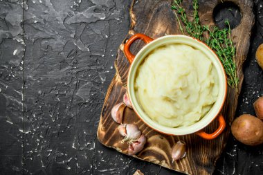 Sarımsak ve kekik ile bir kase patates püresi. Rustik siyah arka plan üzerine.