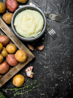 Sarımsak ve kekik ile bir kase patates püresi. Rustik siyah arka plan üzerine.