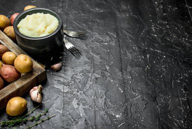 Sarımsak ve kekik ile bir kase patates püresi. Rustik siyah arka plan üzerine.