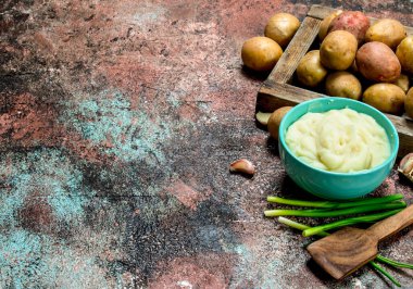 Yeşil soğan ile bir kase patates püresi. Rustik bir arka plan üzerinde.
