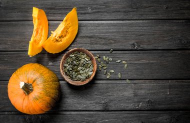 Kabak Çekirdeği bir kase ve olgun kabak parçaları. Ahşap arka plan üzerinde