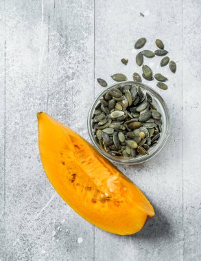 Bir kase de kabak çekirdeği ve olgun kabak bir parça. Rustik arka planda