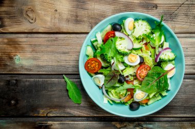 Sebze salatası. Domates, salatalık ve Bıldırcın yumurta salatası zeytinyağı ve fesleğen ile. Ahşap bir arka plan üzerinde.