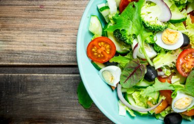 Sebze salatası. Domates, salatalık ve Bıldırcın yumurta salatası zeytinyağı ve fesleğen ile. Ahşap bir arka plan üzerinde.