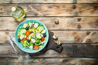 Sebze salatası. Domates, salatalık ve Bıldırcın yumurta salatası zeytinyağı ve fesleğen ile. Ahşap bir arka plan üzerinde.