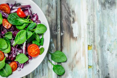 Sebze salatası. Zeytin yağı ile kırmızı lahana, domates, ıspanak salatası. Rustik bir arka plan üzerinde.