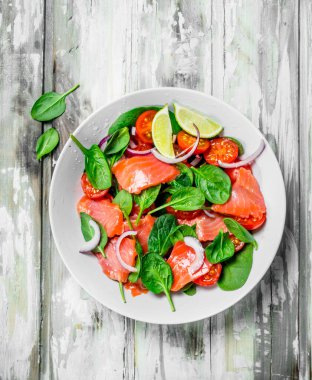 Balık salatası. Dilim somon, domates ve limon suyu ile ıspanak salatası. Rustik bir arka plan üzerinde.