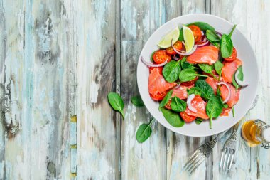 Balık salatası. Dilim somon, domates ve limon suyu ile ıspanak salatası. Rustik bir arka plan üzerinde.