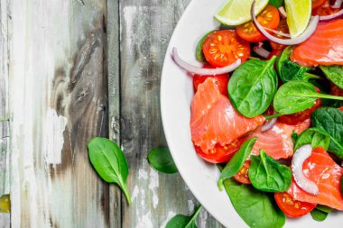 Balık salatası. Dilim somon, domates ve limon suyu ile ıspanak salatası. Rustik bir arka plan üzerinde.