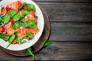 Balık salatası. Dilim somon, domates ve limon suyu ile ıspanak salatası. Ahşap bir arka plan üzerinde.