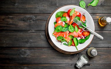 Balık salatası. Dilim somon, domates ve limon suyu ile ıspanak salatası. Ahşap bir arka plan üzerinde.
