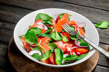 Balık salatası. Dilim somon, domates ve limon suyu ile ıspanak salatası. Ahşap bir arka plan üzerinde.