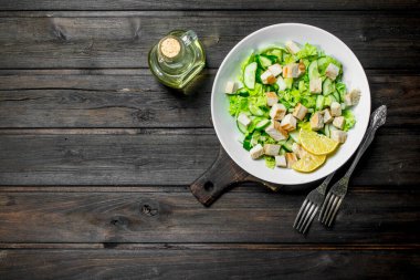 Sağlıklı salata. Salatalık, tavuk ve Çin lahanası salatası limon suyu dökülür. Ahşap bir arka plan üzerinde.