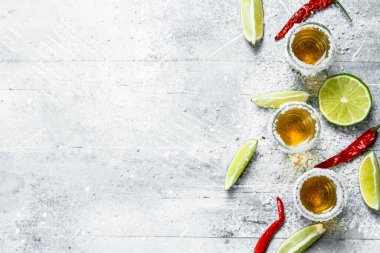 Tekila shot cam kireç ve kırmızı acı biber dilimleri ile. Rustik arka plan üzerinde