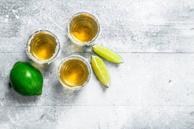 Tekila shot cam kireç dilimleri ile. Beyaz rustik arka plan üzerinde