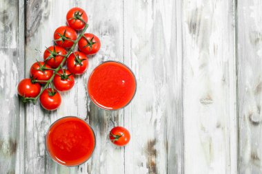 Bir cam ve dal olgun domates domates suyu. Beyaz ahşap arka plan üzerinde