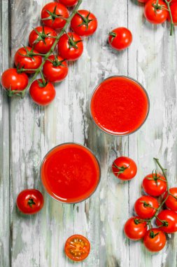 Bir cam ve dal olgun domates domates suyu. Beyaz ahşap arka plan üzerinde