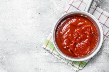 Peçeteli bir tencerede domates sosu. Beyaz rustik arka plan üzerinde