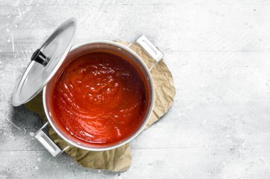 Kağıt üzerinde bir tencerede domates sosu. Beyaz rustik arka plan üzerinde