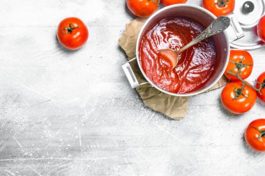 Kağıt ve olgun domates bir kaşık ile bir tencerede Domates sosu. Rustik arka planda