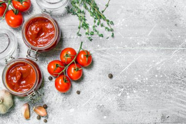 Bir kavanoza otlar, sarımsak ve kiraz domates sosu. Rustik arka plan üzerinde