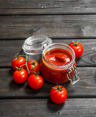 Bir kavanoza Olgun Kiraz domates domates sosu. Ahşap arka plan üzerinde