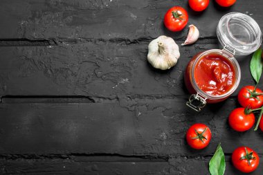 Bir kavanoz domates domates sosu. Rustik siyah arka plan üzerine