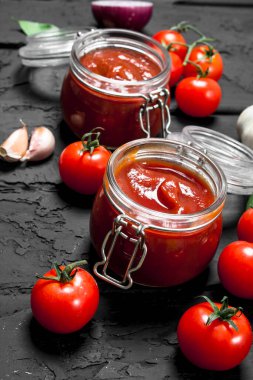 Bir kavanoz domates domates sosu. Rustik siyah arka plan üzerine