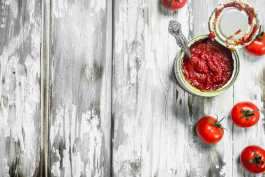 Domates sosu kaşıkla ve domates ile teneke bir kutuda. Beyaz ahşap arka plan üzerinde