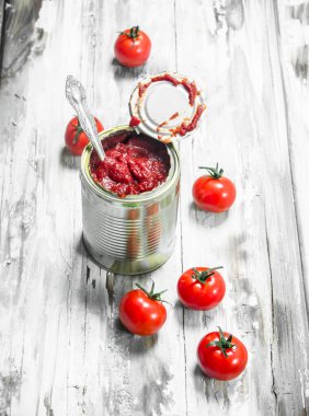 Domates sosu kaşıkla ve domates ile teneke bir kutuda. Beyaz ahşap arka plan üzerinde