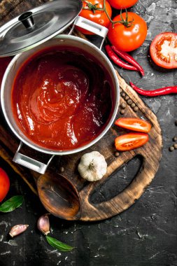 Sarımsak ve domates dilimleri ile kesme Tahtası üzerinde bir tencerede Domates sosu. Rustik arka planda