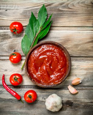 Defne yaprağı, sarımsak ve domates ile kasede Domates sosu. Ahşap arka planda