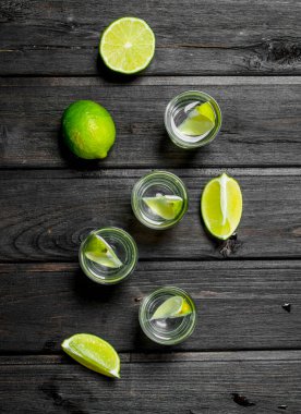 Bardak ve limon dilimlerinde votka. Ahşap arka planda