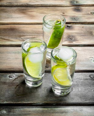 Limon dilimleri ve buzlu votka. Ahşap arka planda