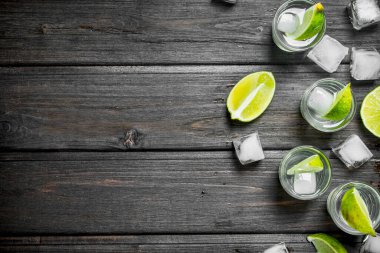 Kireç ve buz bir bardak votka. Siyah ahşap arka plan üzerine