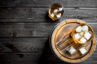 Viski varil üzerinde buz ile gözlük. Siyah ahşap arka plan üzerine