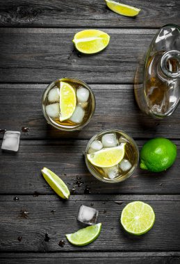 Gözlük ve kireç dilimleri bir şişe viski. Siyah ahşap arka plan üzerine