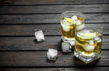 Buz ve limon dilimleri ile bardaklarda viski. Ahşap arka plan üzerinde