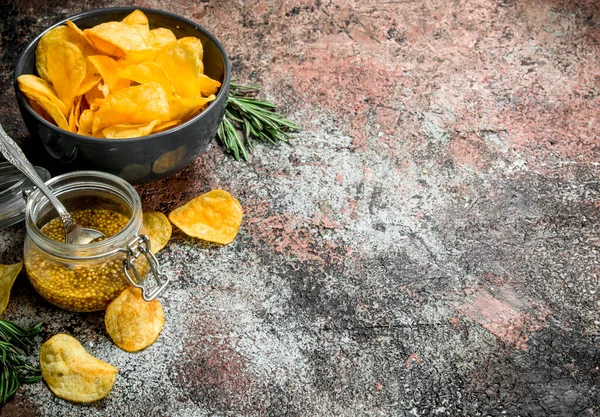 stock image Potato chips with French mustard and rosemary. On a rustic background.