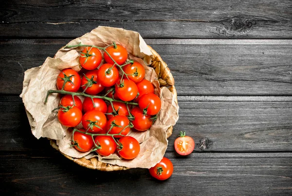 stock image Ripe tomatoes on a branch in the basket. On wooden background