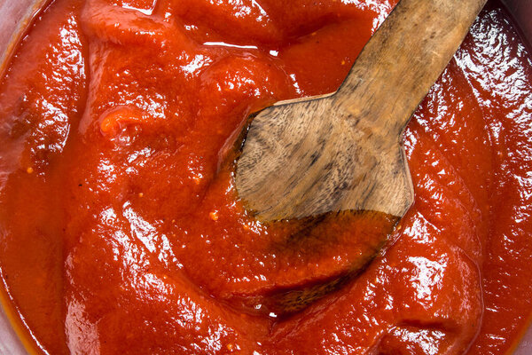 Tomato sauce with a wooden scoop. Top view