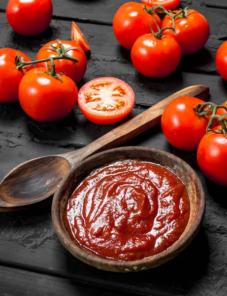 ボウルにスプーンと熟したトマトのトマトソース 黒い素朴な背景に — ストック写真