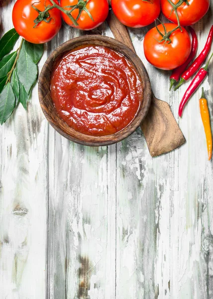 番茄酱在碗里与勺子 海湾叶和辣椒 在木背景 — 图库照片