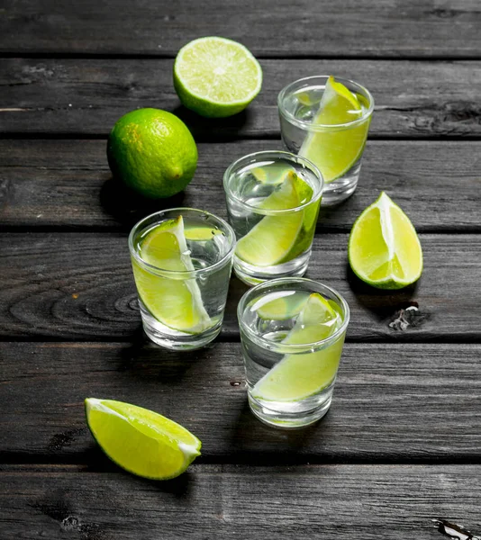 Vodka Plátky Čerstvého Vápna Střílené Sklenici Dřevěném Pozadí — Stock fotografie