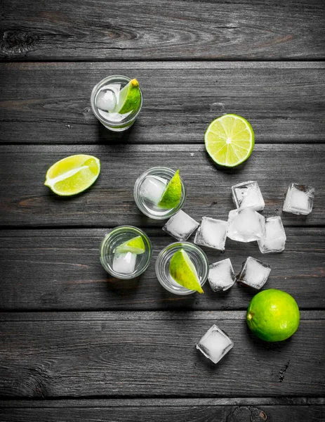 Votka bir fondip bardakları buz ve limon dilimleri ile. Ahşap arka plan üzerinde