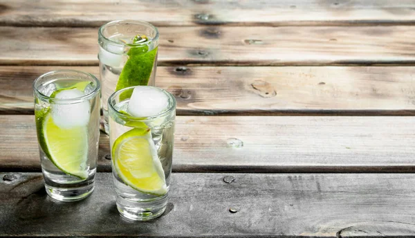 Limon dilimleri ve buzlu votka. Ahşap arka planda