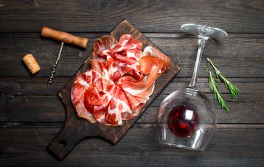 Bir bardak kırmızı şarap ile İspanyolca jambon. Ahşap bir arka plan üzerinde.