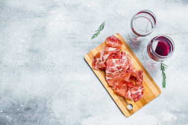 Bir bardak kırmızı şarap ile İspanyolca jambon. Rustik bir arka plan üzerinde.