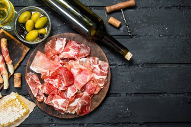 Kırmızı şarap ve breadsticks ile İspanyolca jambon. Rustik siyah arka plan üzerine.